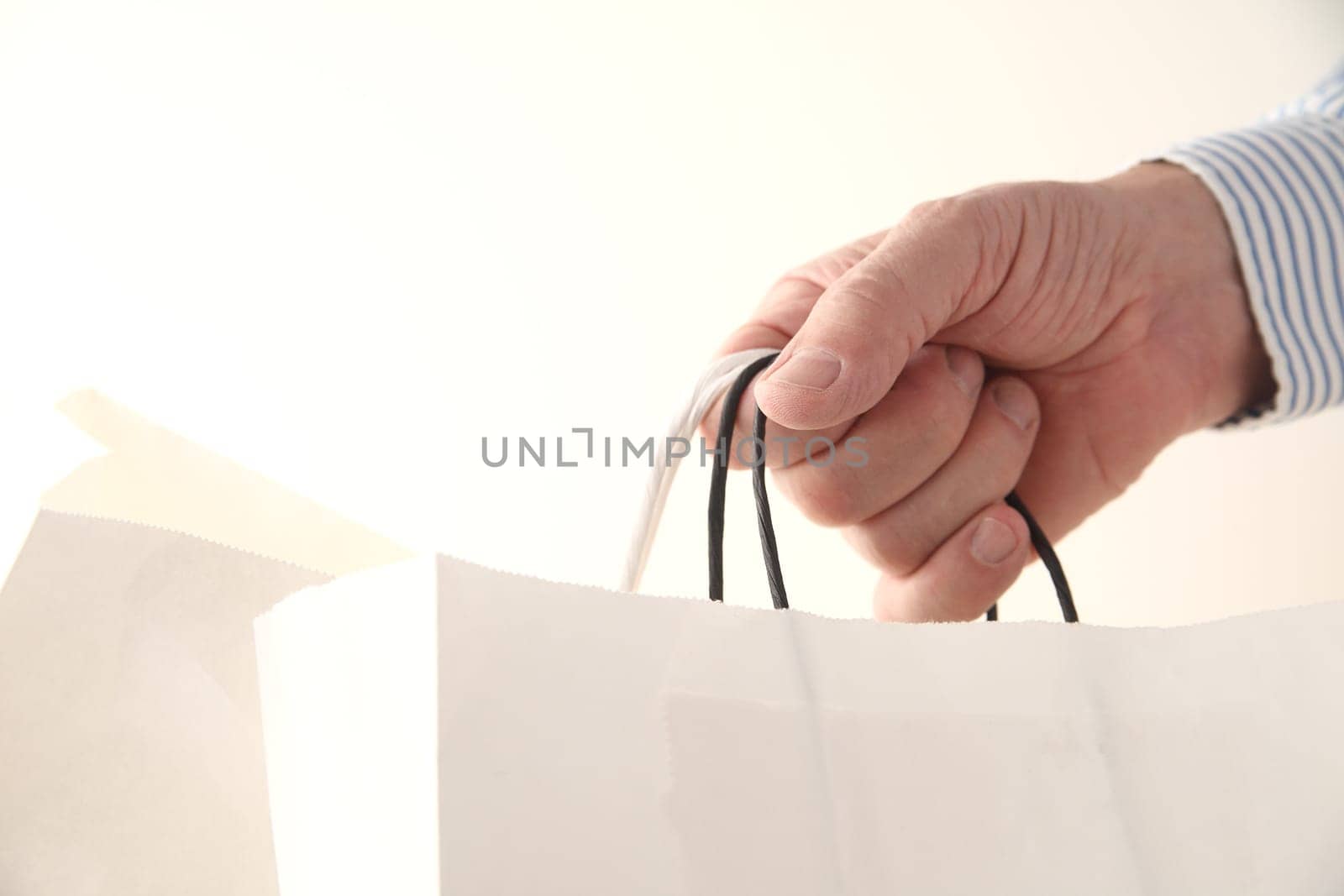 a man's hand with two store paper bags