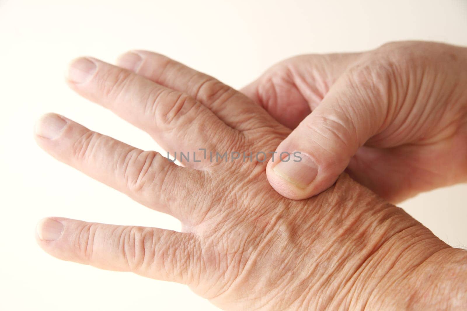 senior man massages the pain on a knuckle