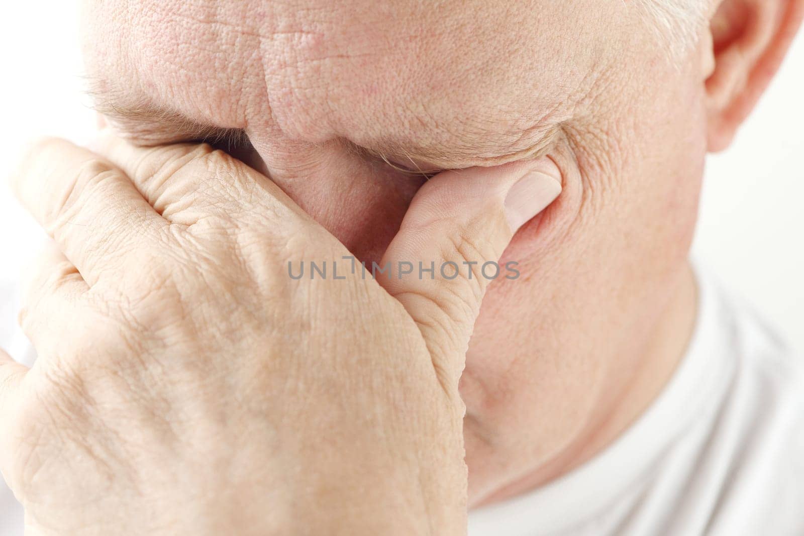 overworked older man tries to relieve his eyestrain