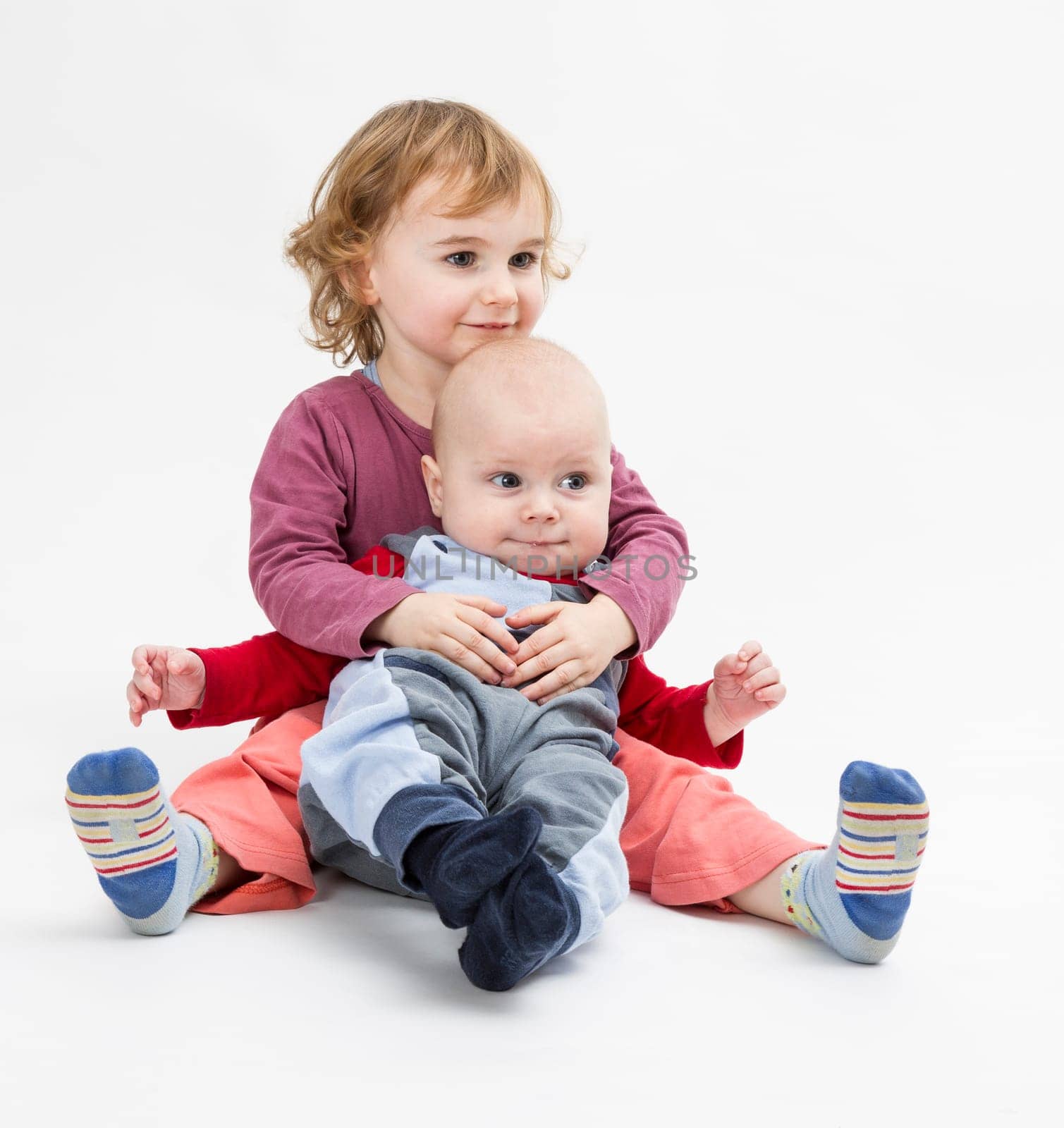 baby boy with 3 year old sister sitting in light background