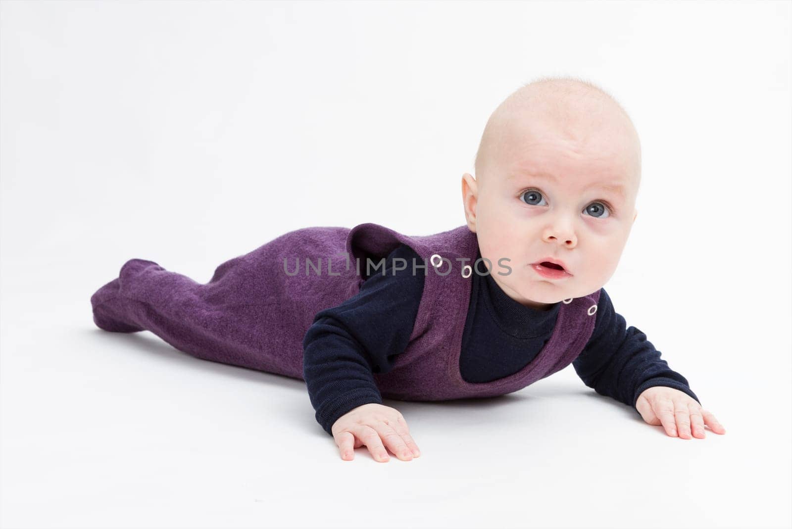 baby on floor looking to camera. studio shot in grey background