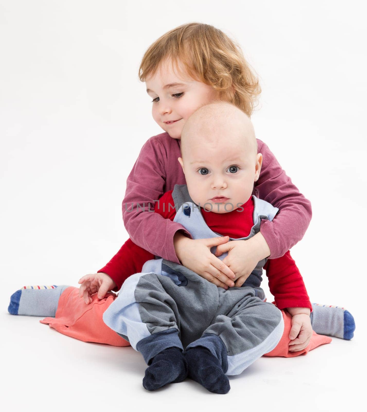 baby boy with 3 year old sister sitting in light background