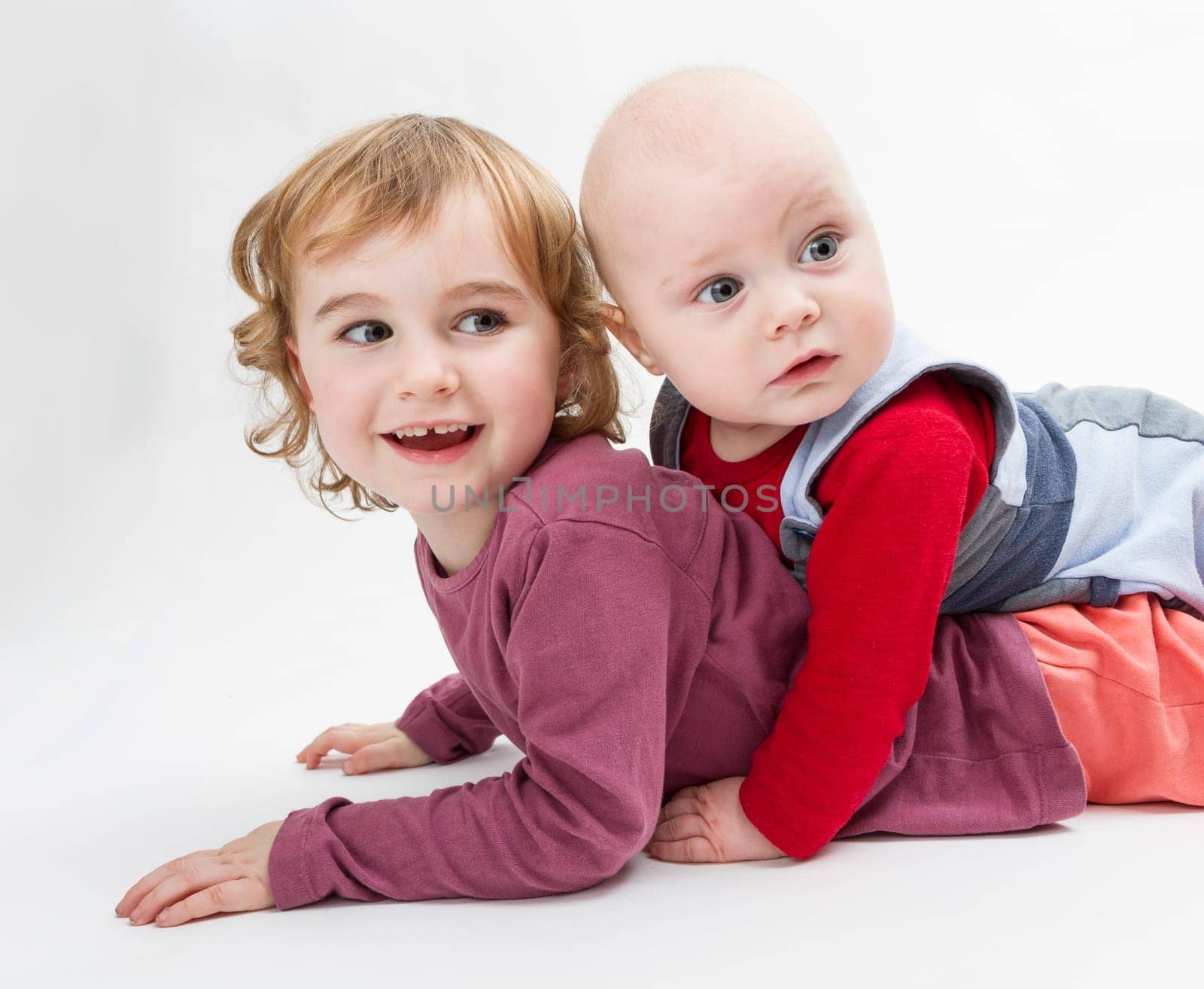 two siblings playing on floor. studio shot in grey background