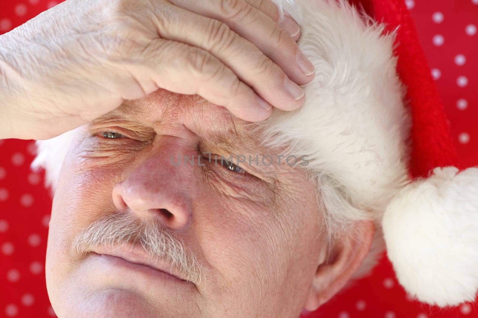 senior man in Santa hat with a headache