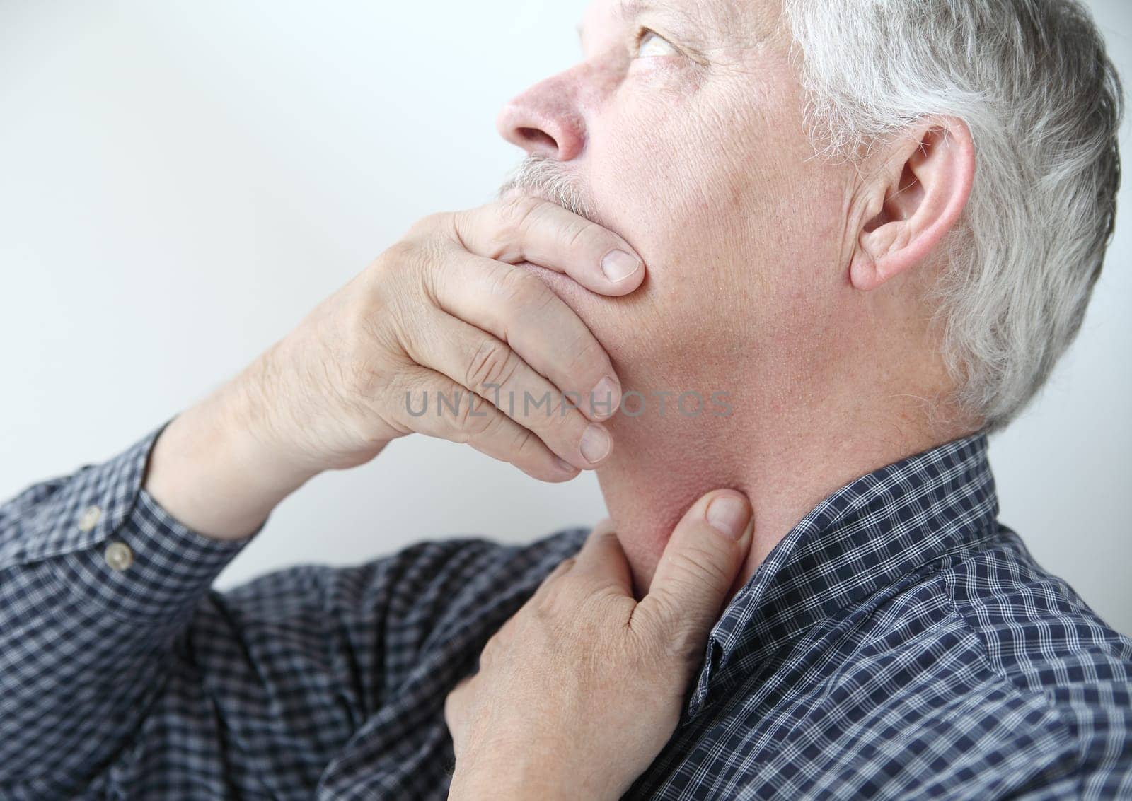 senior man touches area on neck where he feels pain