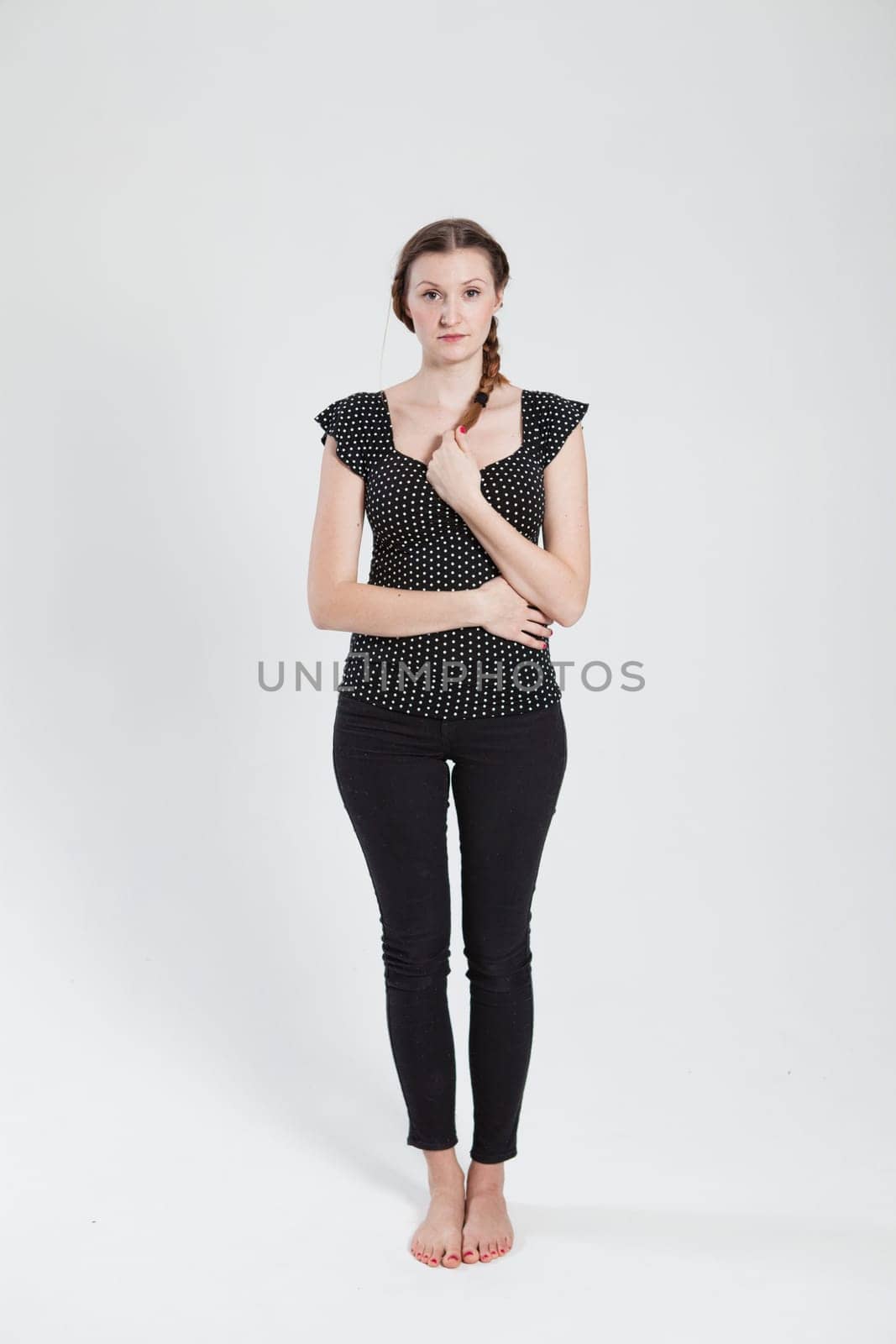Studio portrait of thoughtful looking attractive woman holding her pigtail