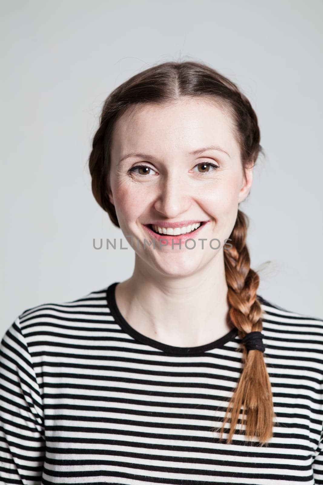 Closeup studio portrait of happy smiling attractive woman with pigtail wearing striped blouse