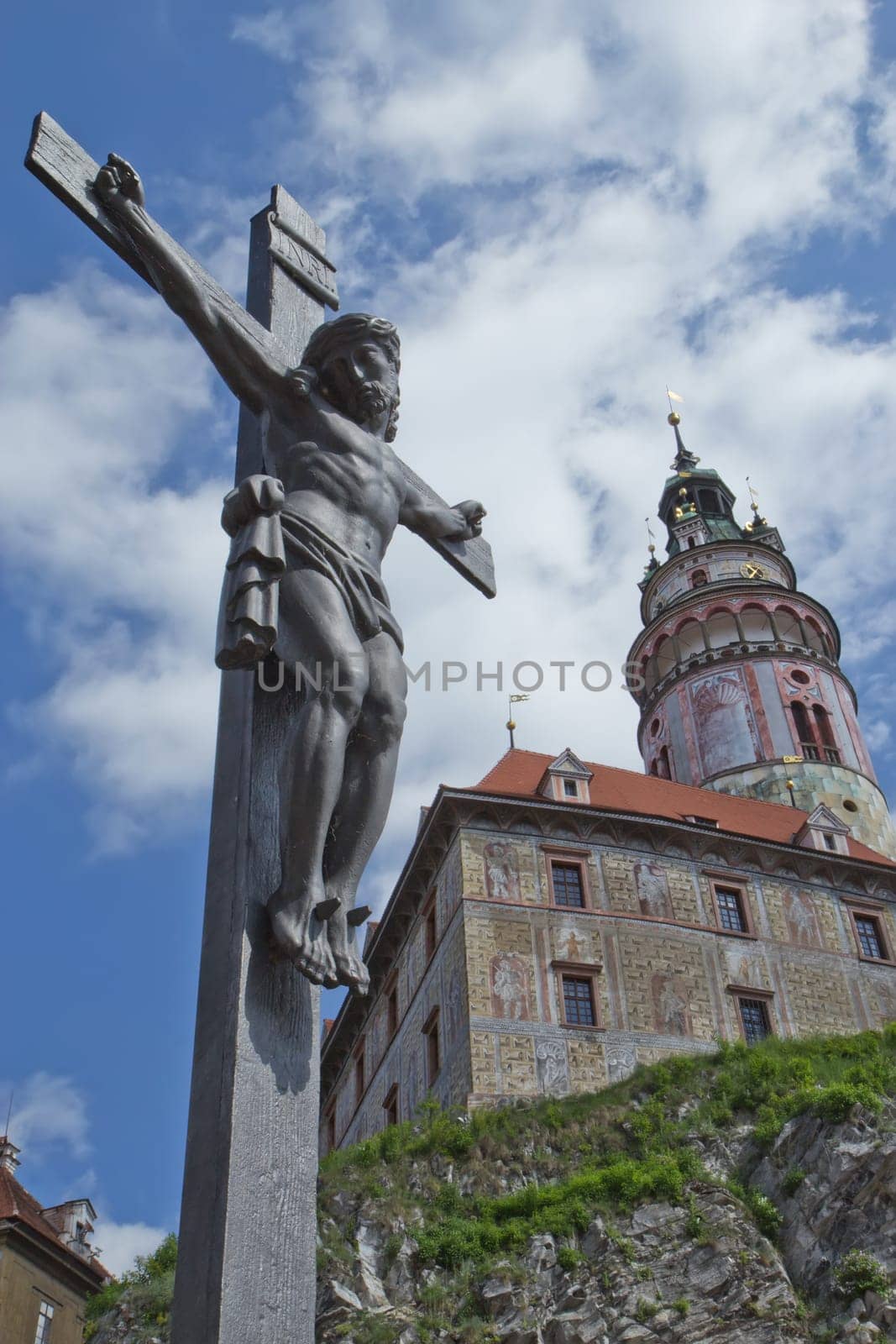 View of the statue of the Christ on the cross and the castle Cesky Krumlov in the background