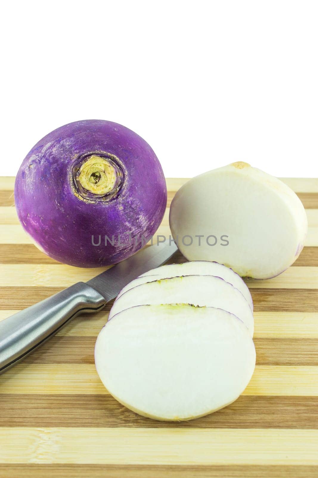 purple headed turnips with slices and knife on wood board.