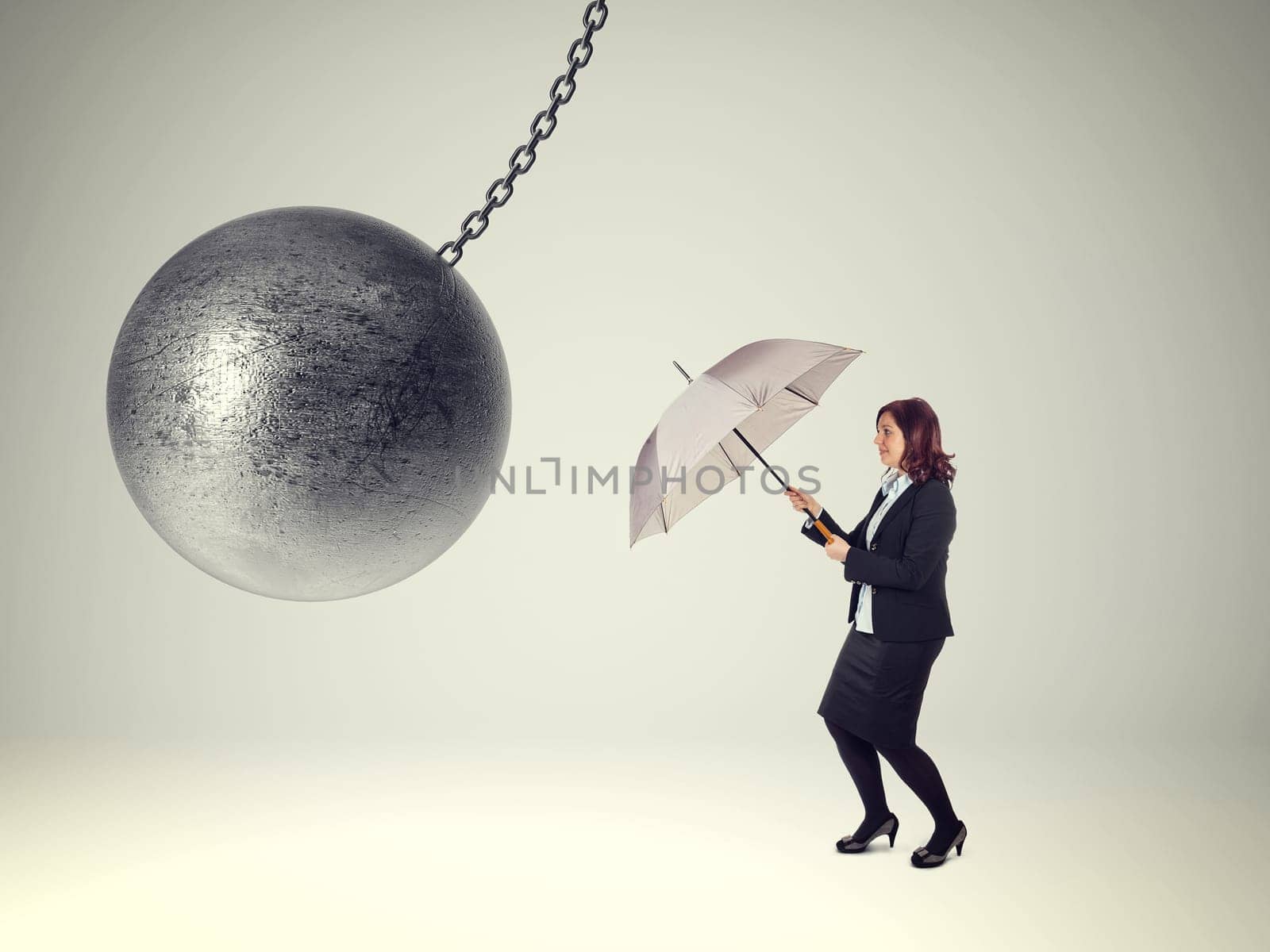 businesswoman with umbrella and heavy iron ball