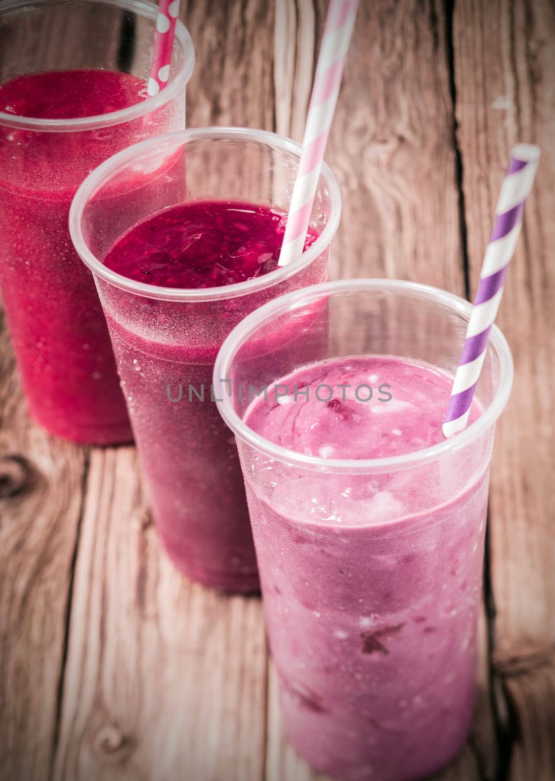 Healthy delicious trio of different berry smoothies with low fat yogurt arranged in a diagonal row, high angle view on an old rustic wooden background