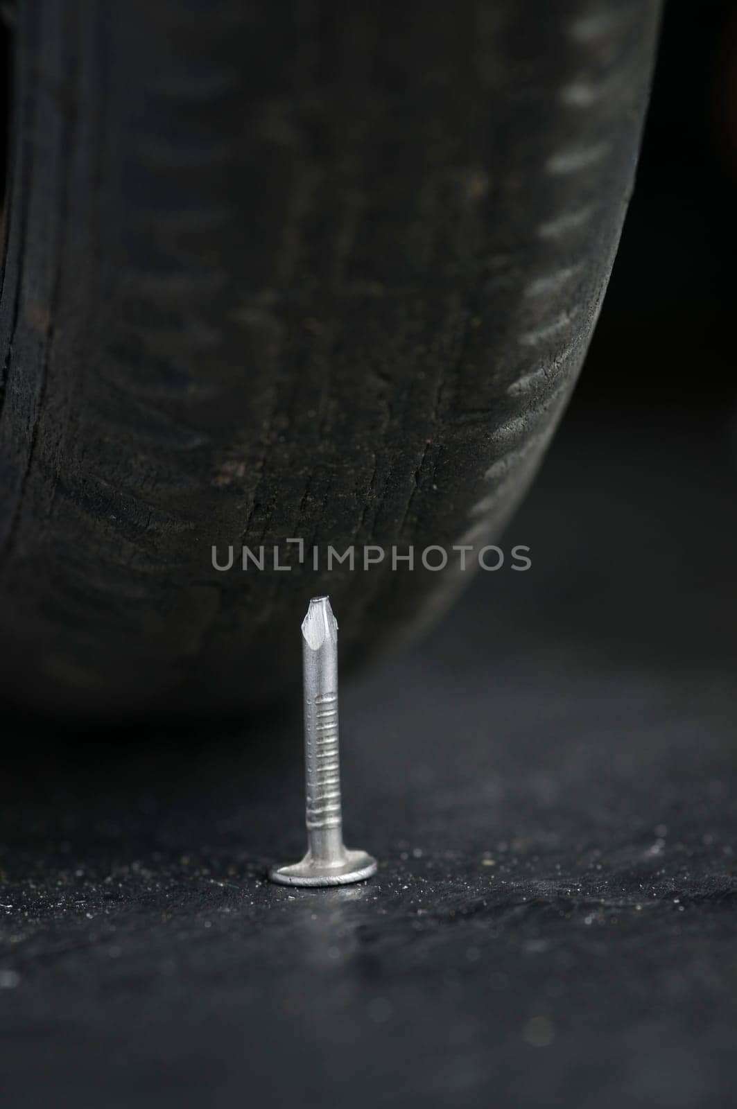 Close-up with low depth of field of a vehicle tire and a nail in front of it