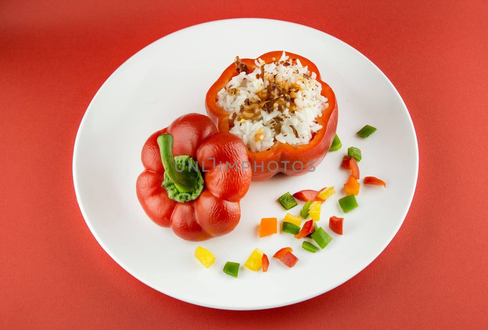 Stuffed red pepper in a dish on red background .