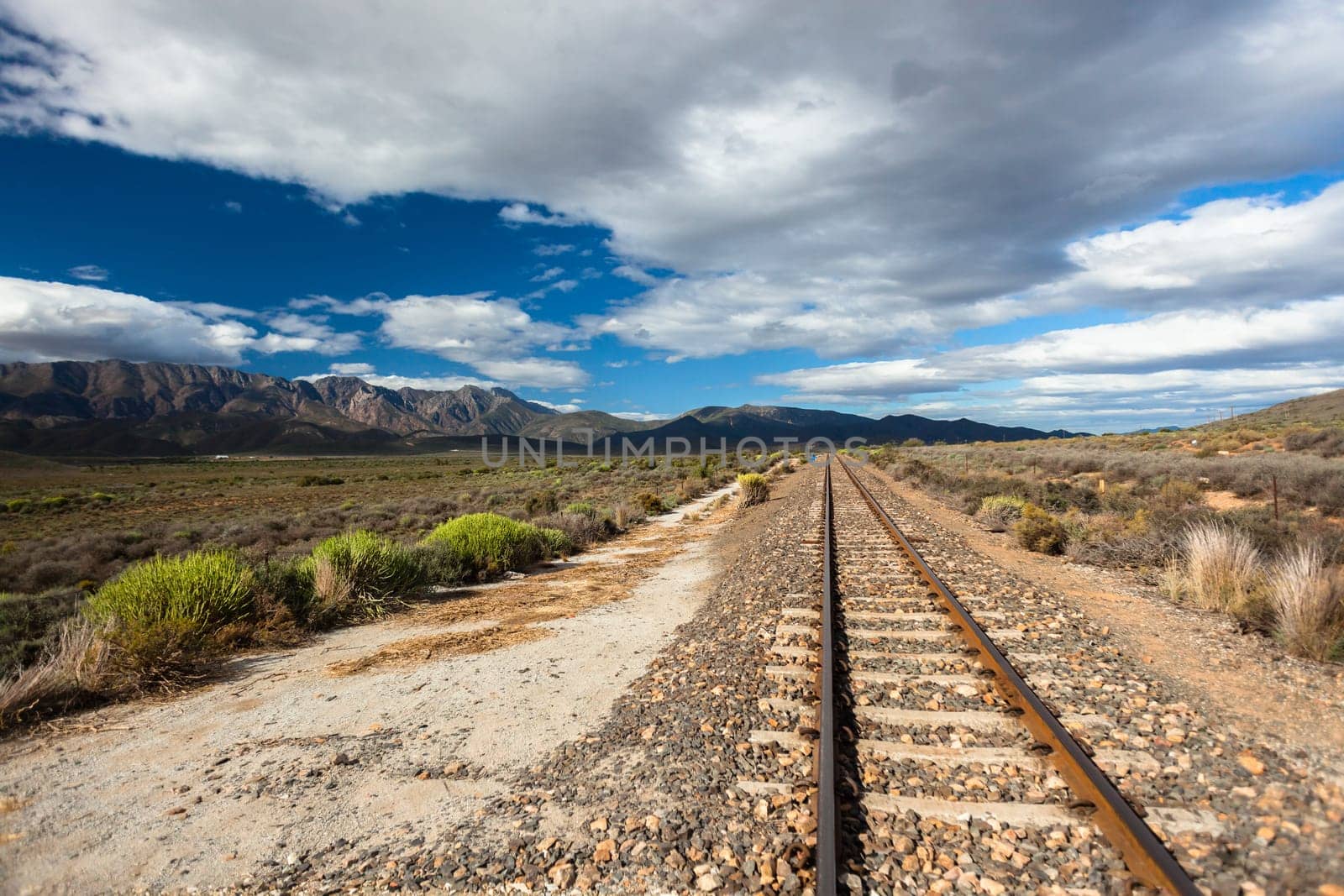 Rail track single line travels over the rugged rural wilderness landscape plateau nearby distant mountains