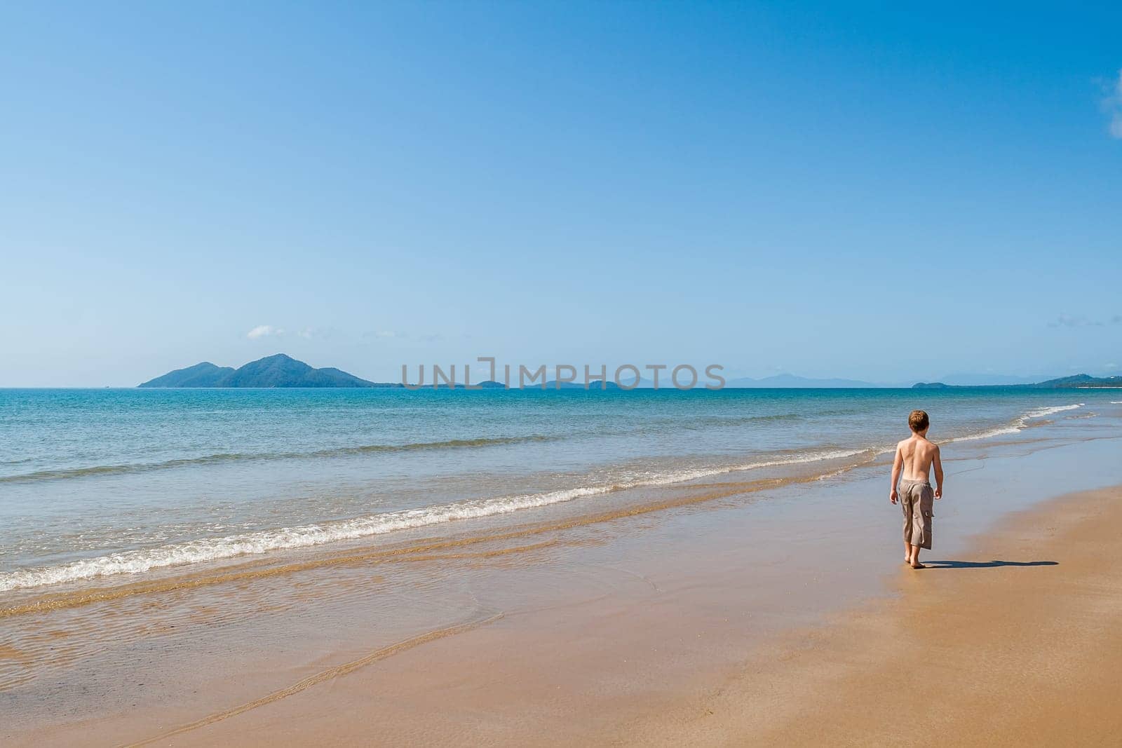 Boy in waters walking along tropical waters at  mission beach nearby Cairns Queensland Australia