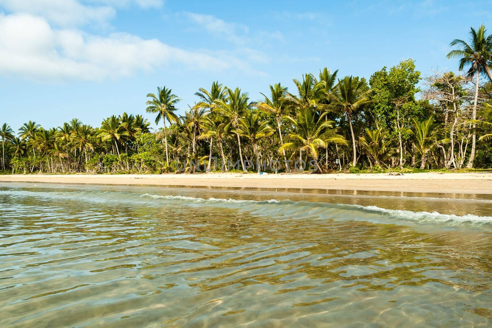 Couple man woman unidentified carrying kayak into tropical waters at  mission beach nearby Cairns Queensland Australia