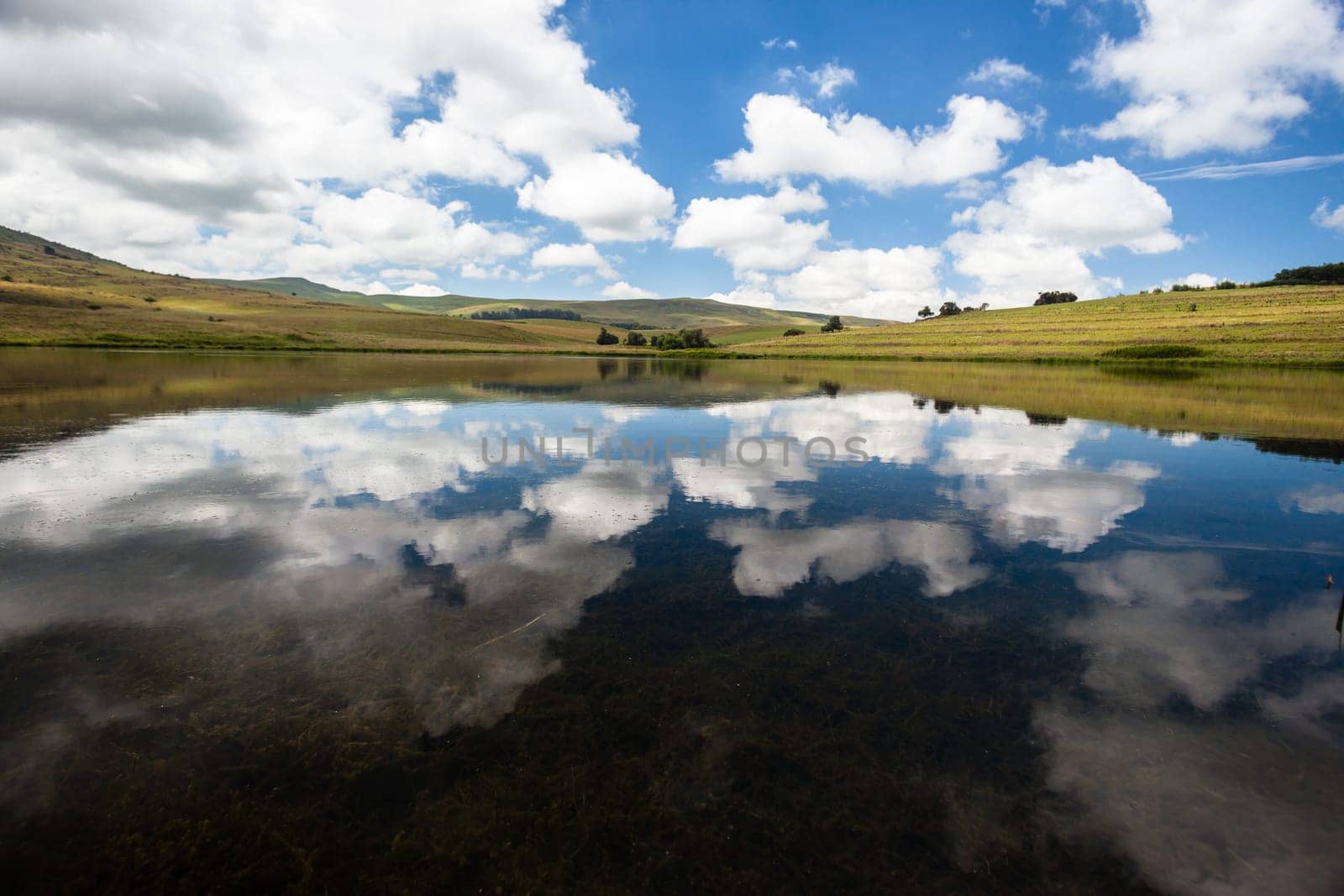 Small mountain lake dam with glass mirror reflections of clouds and blue sky over scenic beauty landscape