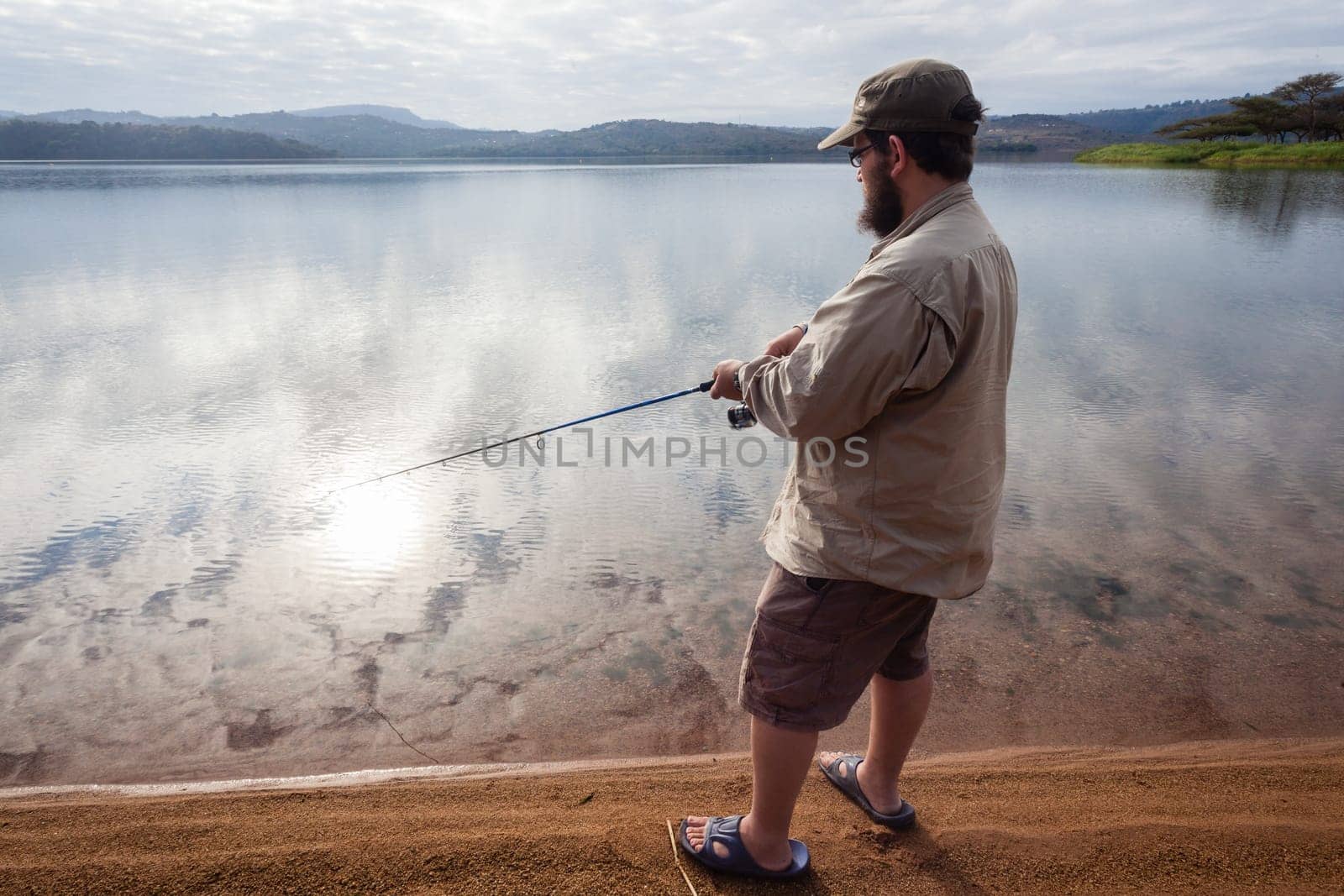 Fisherman closeup fishing on smooth glass dam waters landscape