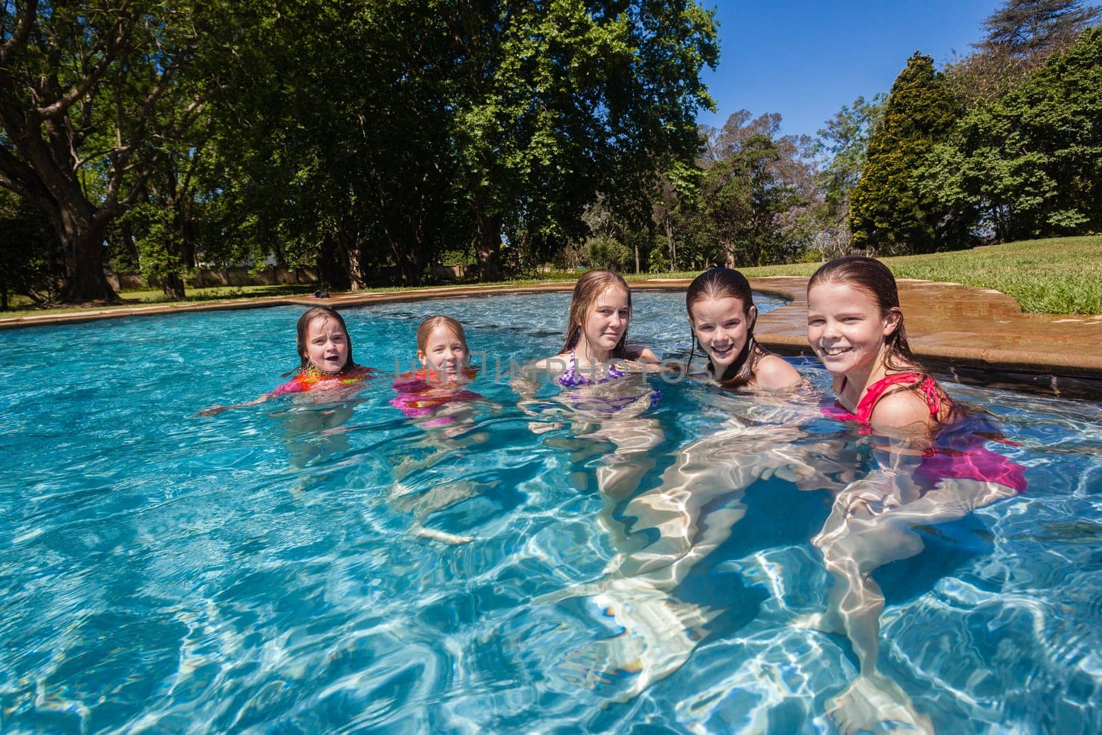 Girls cousins teenagers in home swimming pool playtime outdoors summer