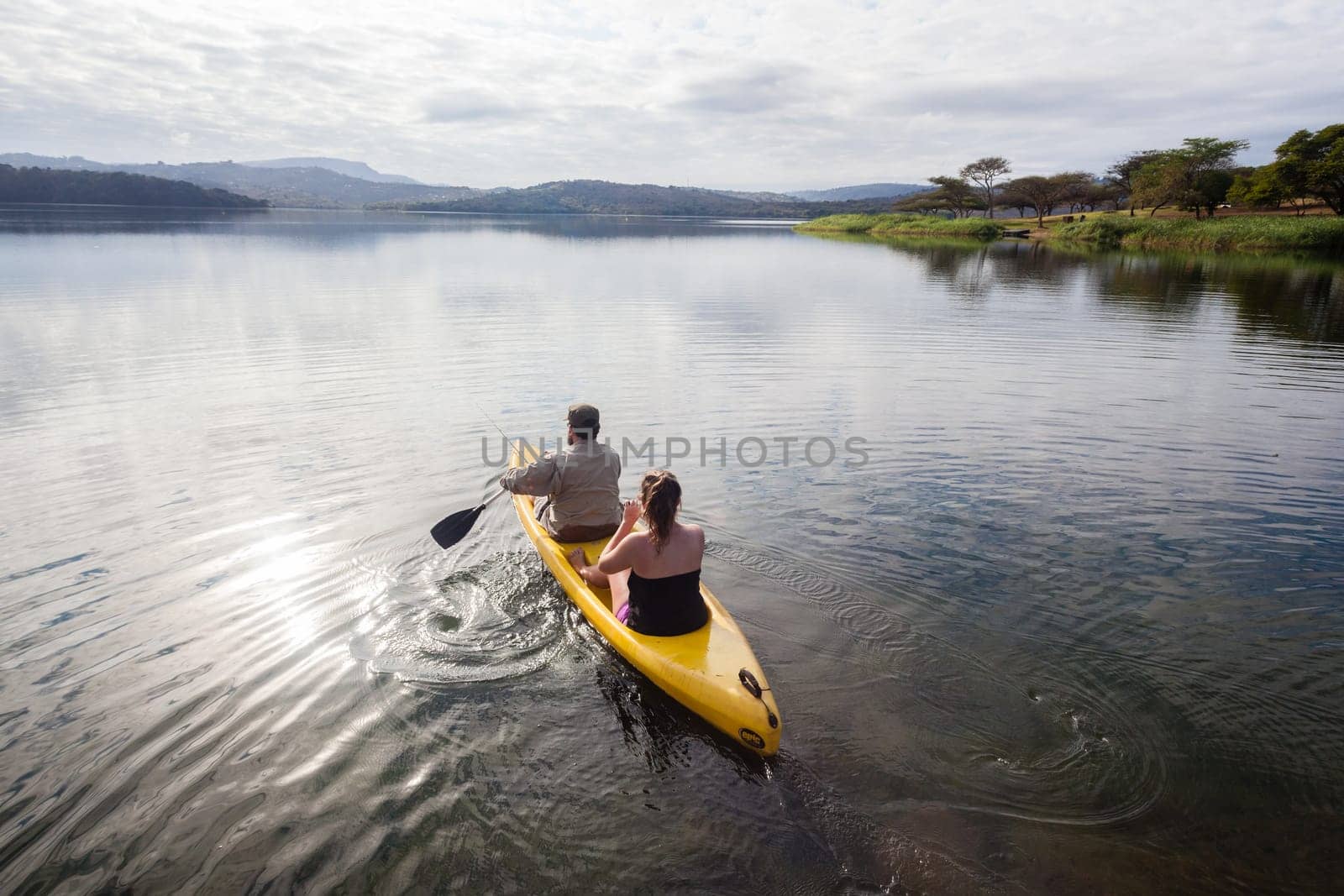 Teenage girls going out on yellow canoe to explore dam lake waters and shoreline