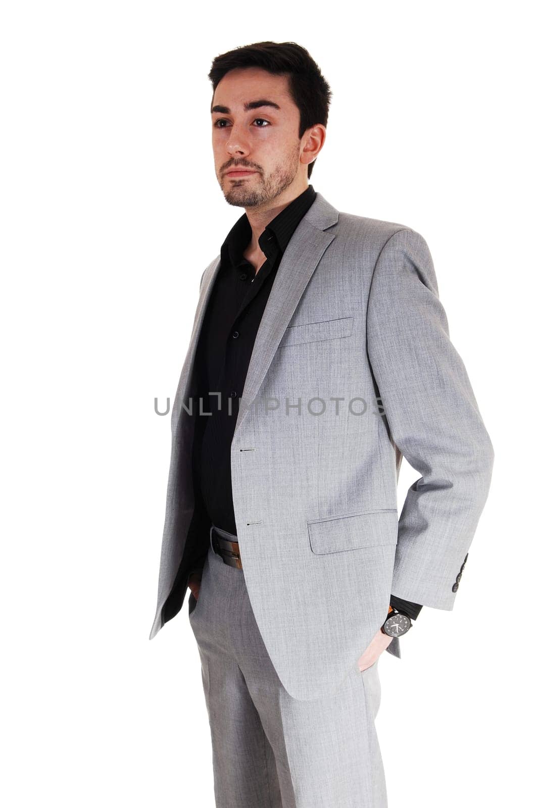 A tall handsome businessman standing isolated for white background .in a grey suit with his hands in his pocket..