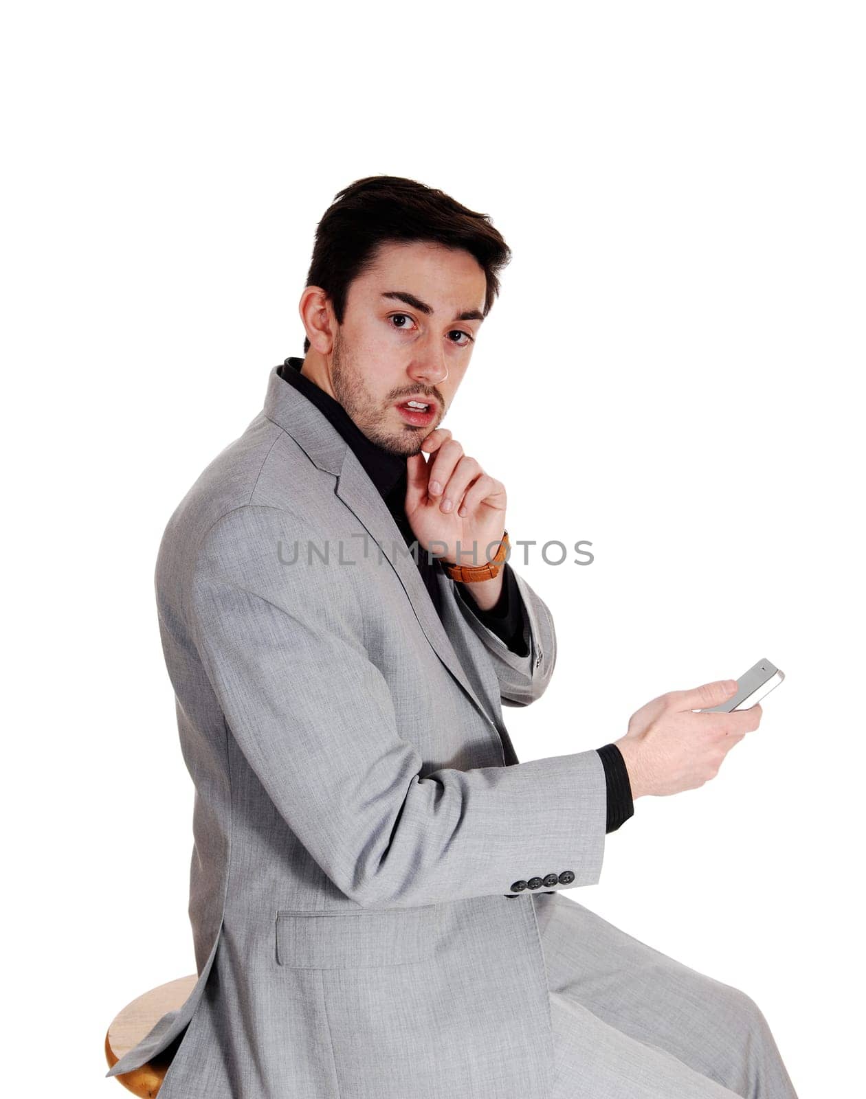 A young man holding on a cell phone in a black shirt with a beard, looking.very scared, isolated for white background..