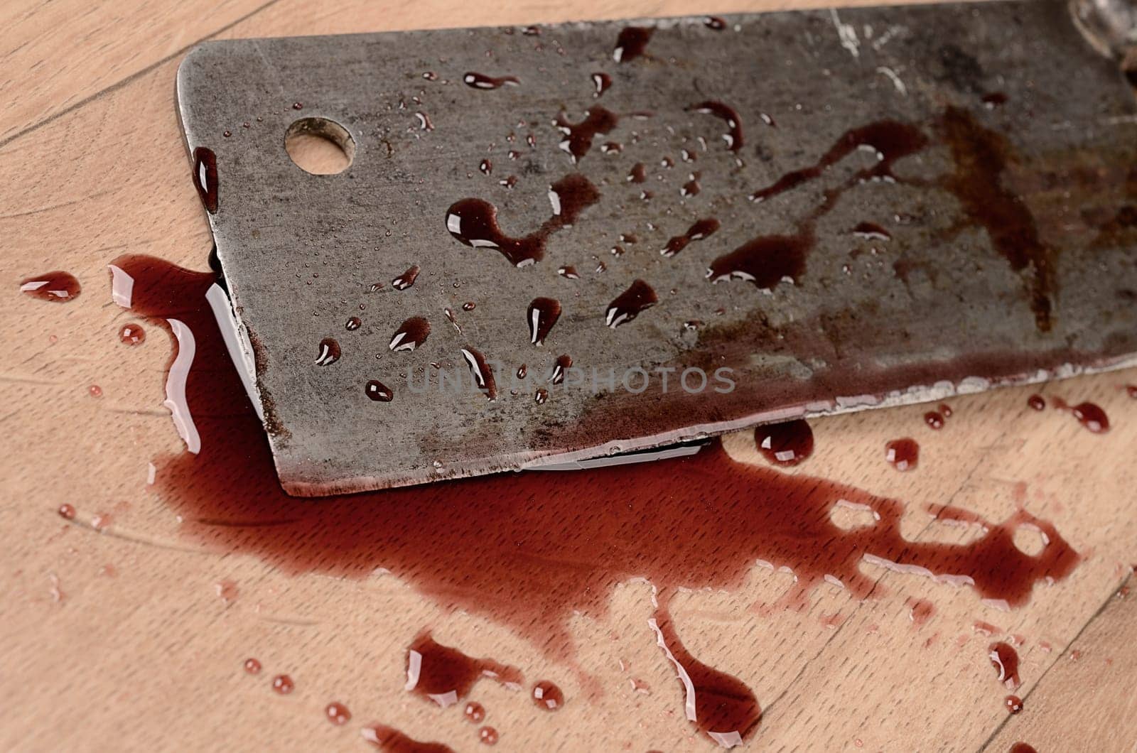Old rusty meat cleaver with blood on a wooden floor