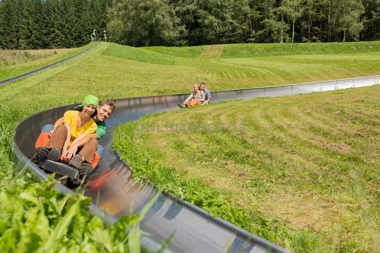 Smiling young couples enjoying summer sledge ride