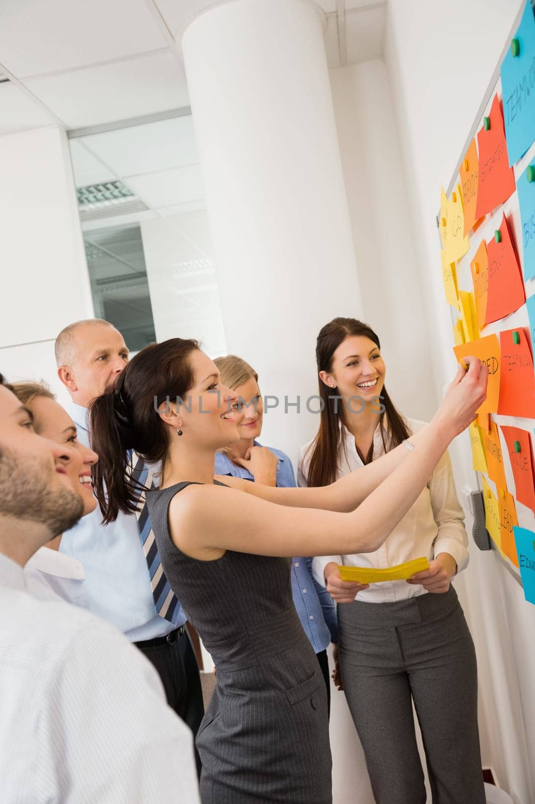 Businesswoman sticking labels on whiteboard during meeting