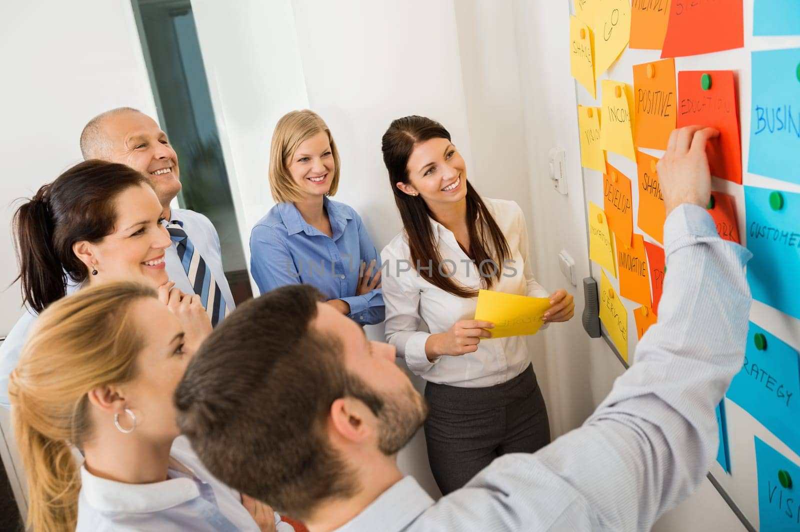 Businessman explaining labels on whiteboard to colleagues in meeting