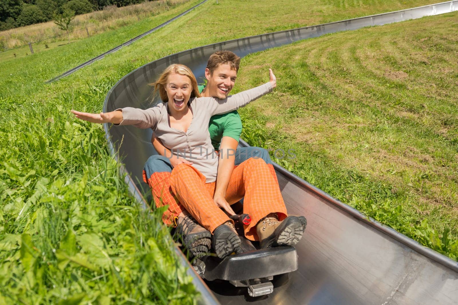 Excited young couple enjoying alpine coaster luge during summer