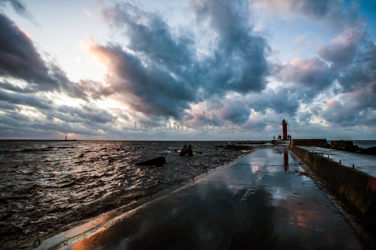 fragment of concrete,wet of rain breakwater with visible raugh sea,dramatic sun set and clouds,visible storm lantern,lighthouse.