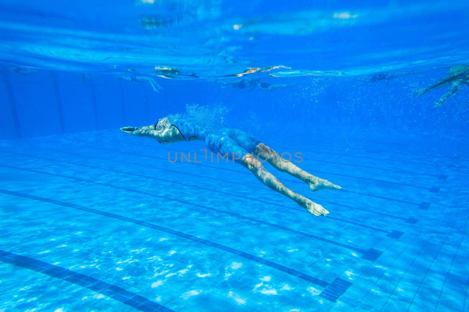 Swimmers girls boys warm-up laps before race heats.Underwater swimming water action at national championships.