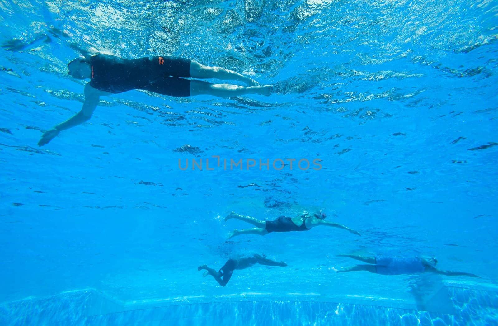 Swimmers girls boys warm-up laps before race heats.Underwater swimming water action at national championships.