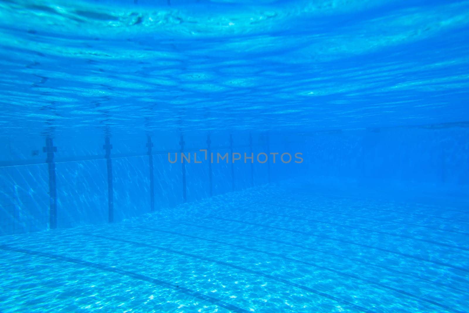 Underwater swimming pool waters towards surface and blue sky