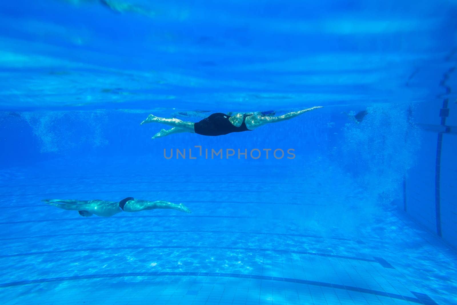 Swimmers girls boys warm-up laps before race heats.Underwater swimming water action at national championships.
