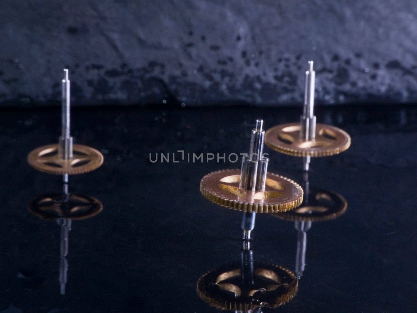 Close-up three fast-rotating gears on water-covered slate slab