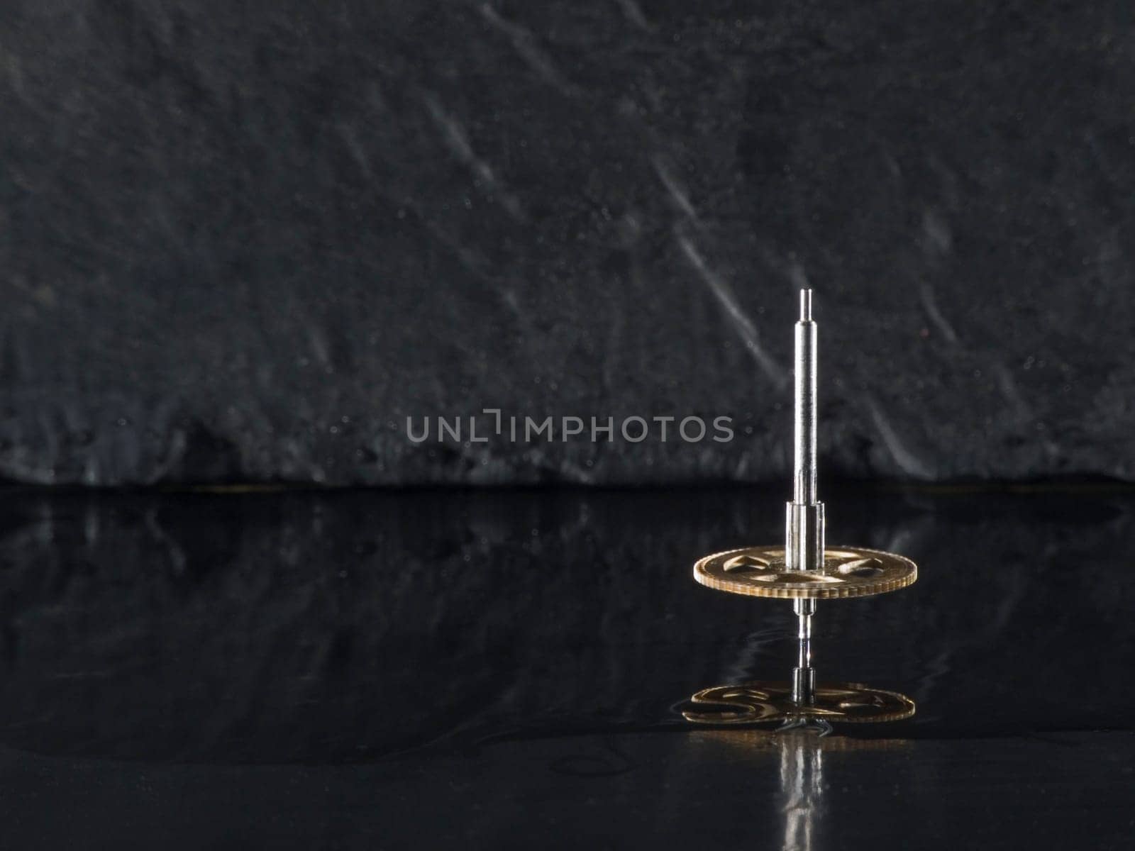 Close-up three fast-rotating gears on water-covered slate slab