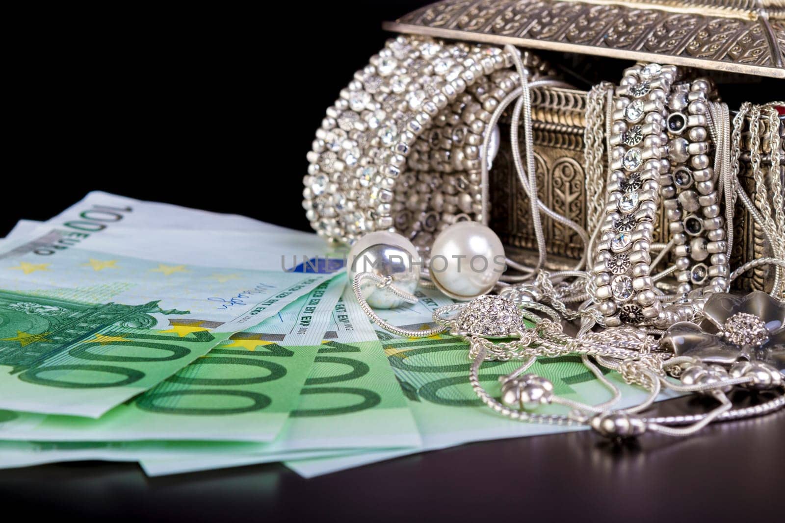 Silver jewelry and Euro on black background.