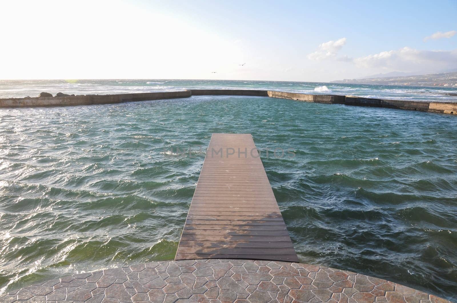 Empty Wooden Pier With Sea And Cloudy Sky On Background