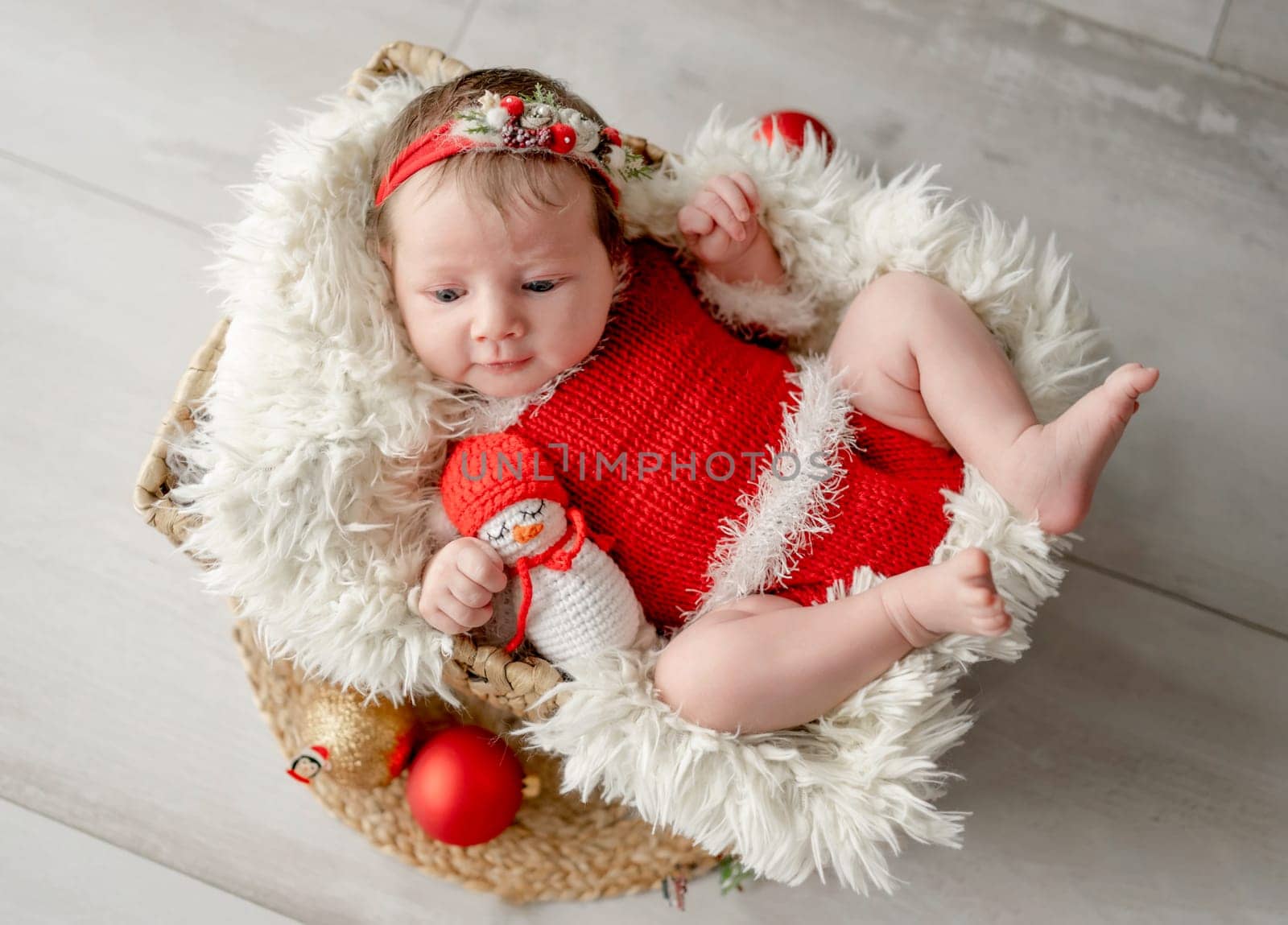 Newborn baby girl wearing Santa Christmas costume sleeping in basket with xmas decoration. Little infant child New Year portrait