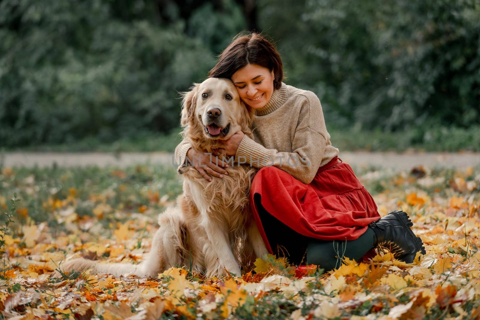 Young woman in autumn park with her golden retriever dog