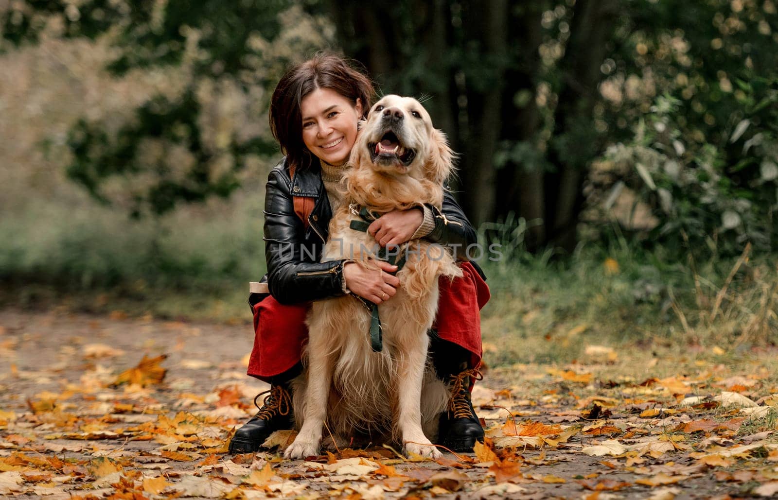 Young woman in autumn park with her golden retriever dog