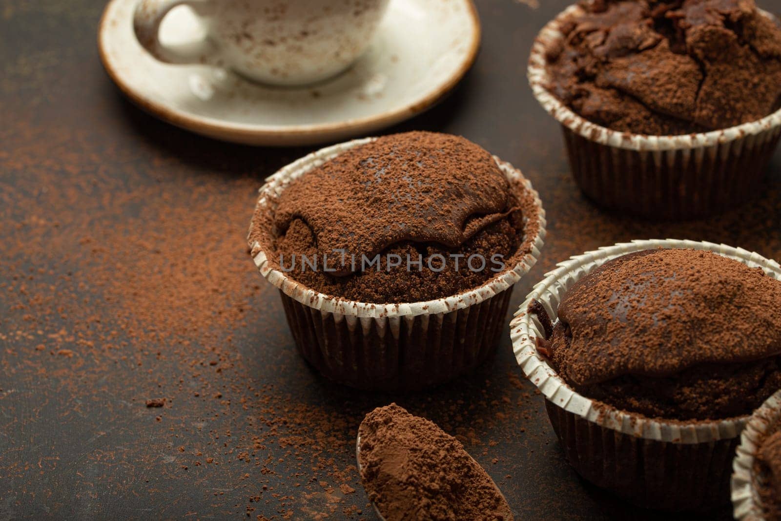 Chocolate and cocoa browny muffins with coffee cappuccino in cup angle view on brown rustic stone background, sweet homemade dark chocolate cupcakes, space for text.