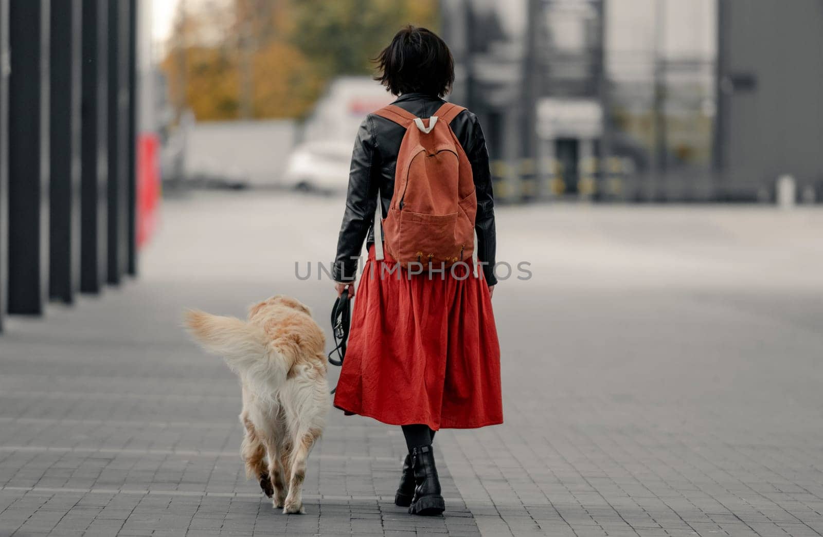 Young woman walking down the street with her golden retriever dog