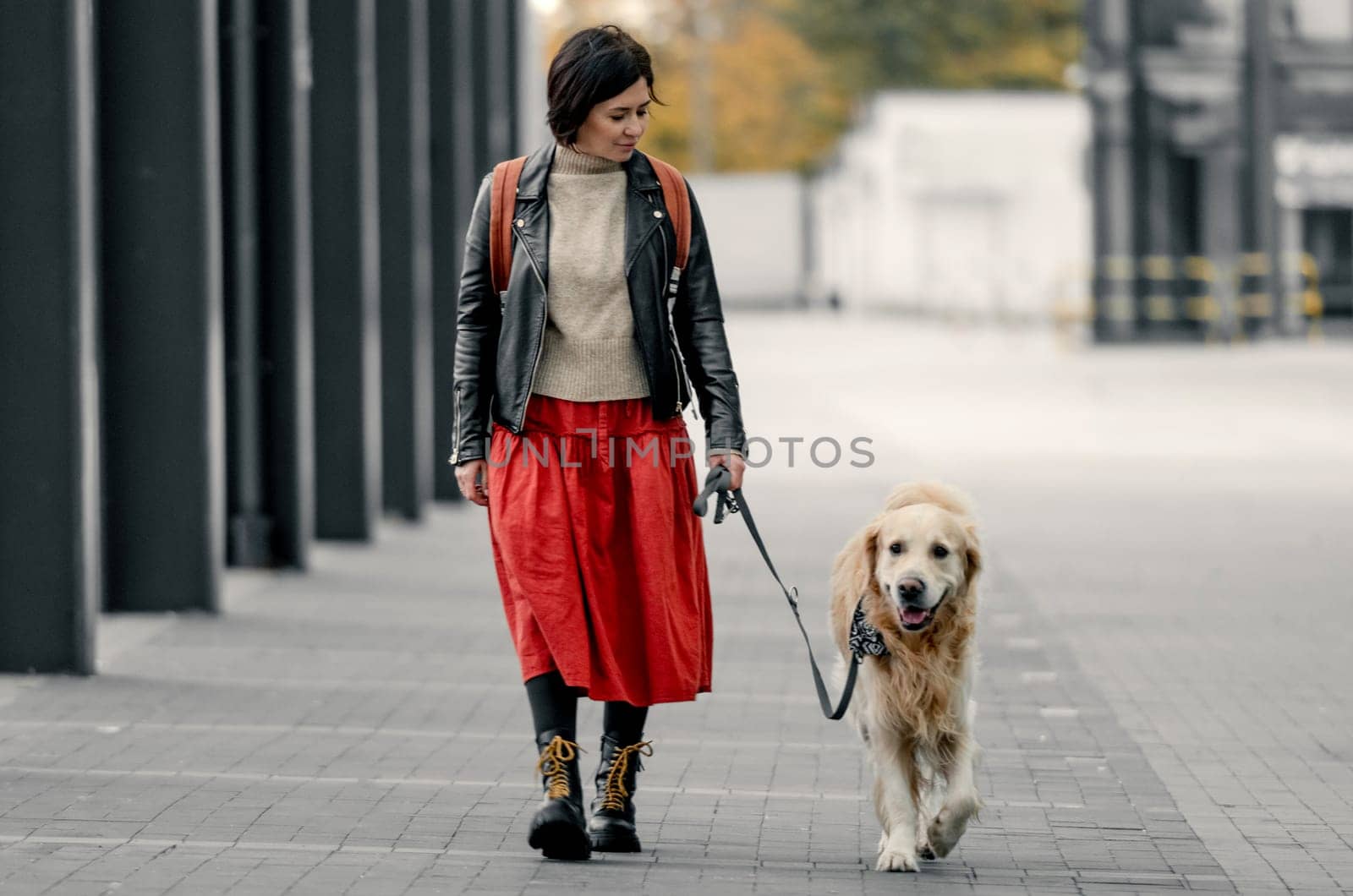 Young woman walking down the street with her golden retriever dog