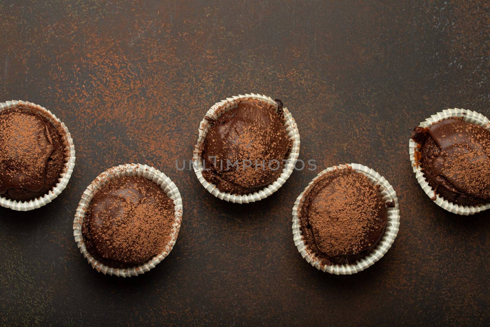 Chocolate and cocoa browny muffins top view on brown rustic stone background, sweet homemade dark chocolate cupcakes by its_al_dente