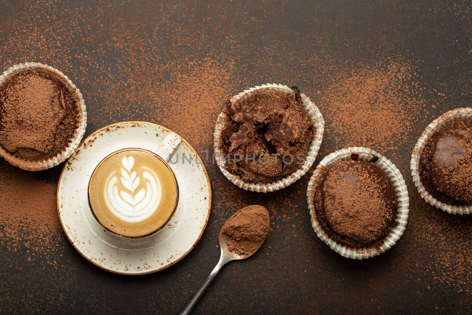 Chocolate and cocoa browny muffins with coffee cappuccino in cup top view on brown rustic stone background, sweet homemade dark chocolate cupcakes by its_al_dente