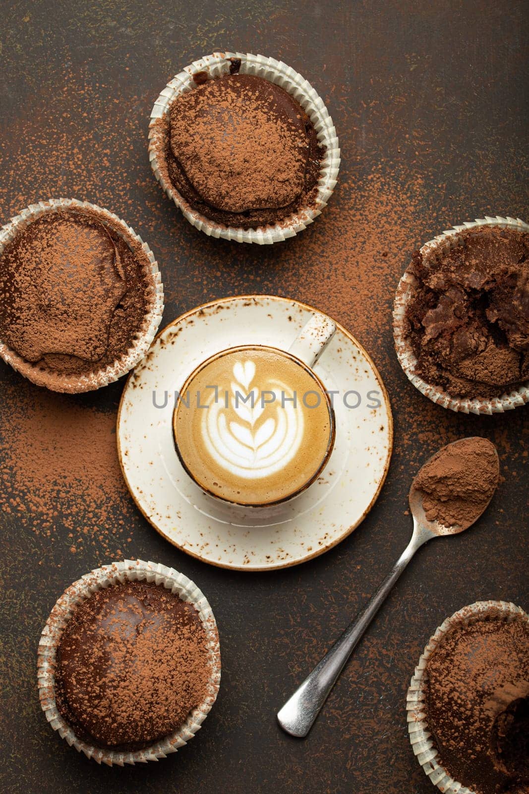 Chocolate and cocoa browny muffins with coffee cappuccino in cup top view on brown rustic stone background, sweet homemade dark chocolate cupcakes by its_al_dente