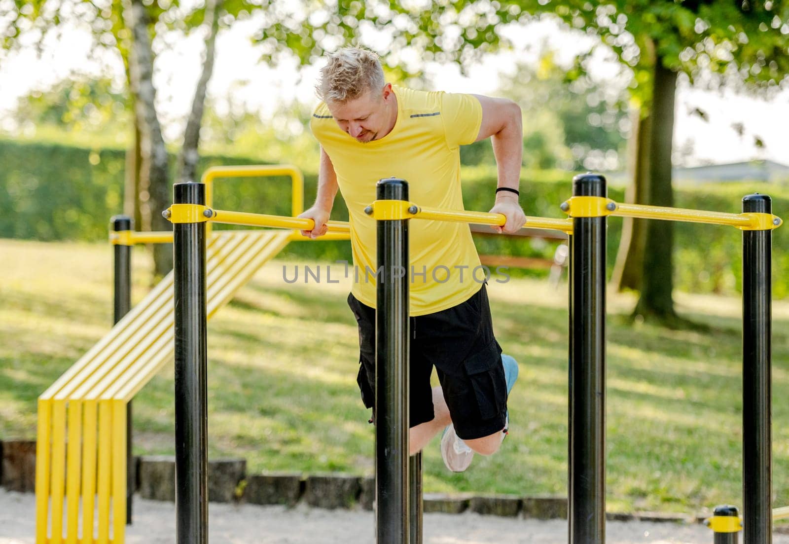 Man excersing with horizontal bar outdoors by tan4ikk1